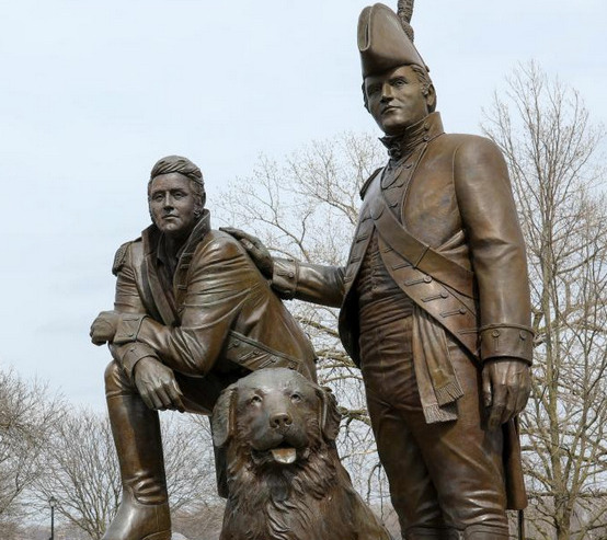A bronze historical monument statue of a soldier and a dog standing outdoors.