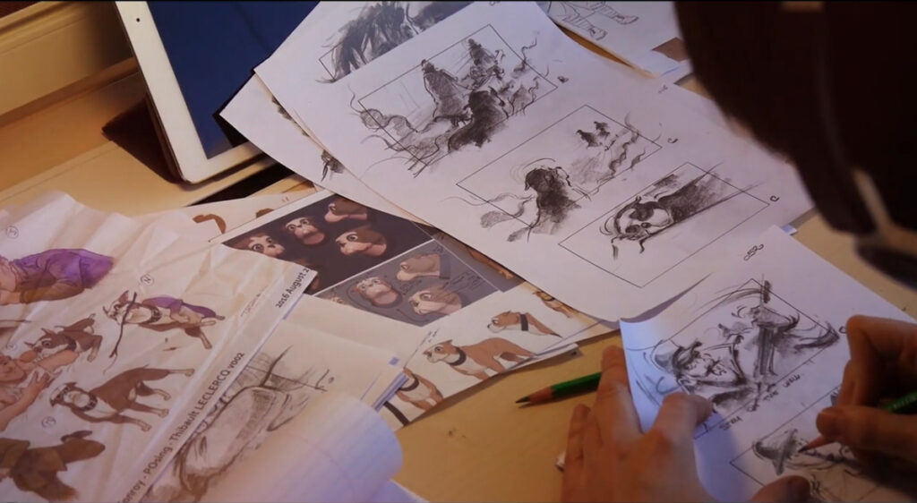 A desk cluttered with rough pencil sketches, storyboards, and animation concept designs.